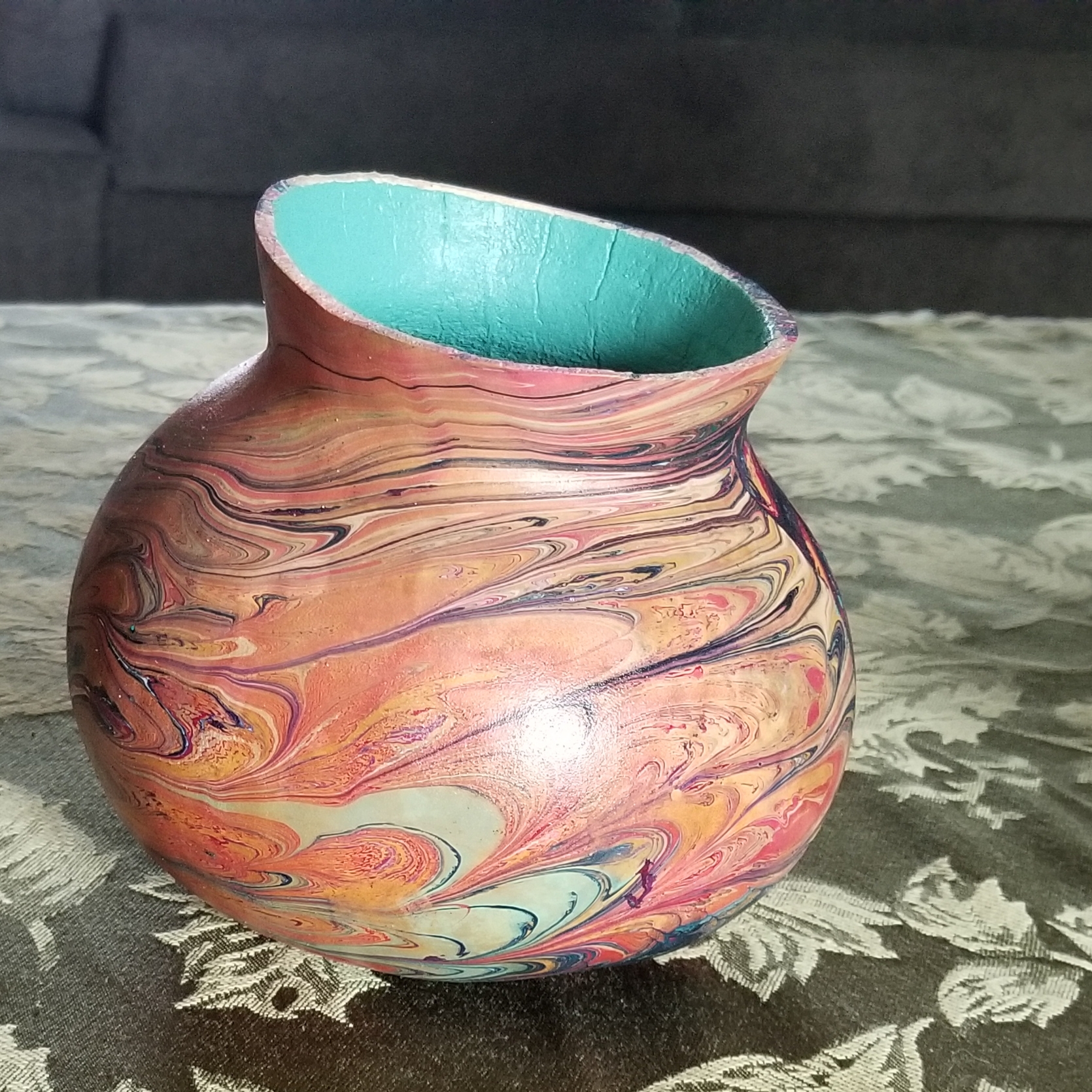 A round short gourd with a swirl pattern created through hydrodipping. The inside of the gourd is painted light blue